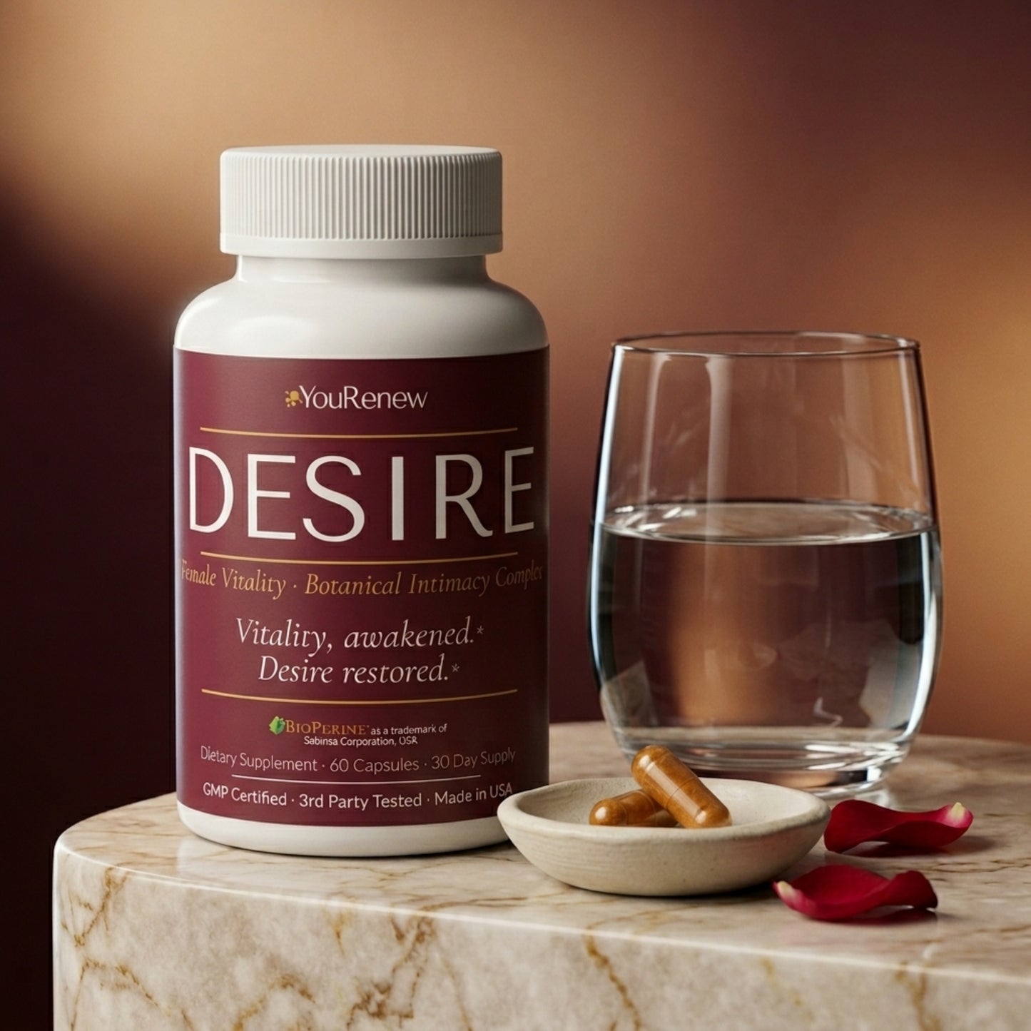 Daily ritual setup with YouRenew DESIRE bottle, water glass, and two amber capsules in ceramic dish on marble surface